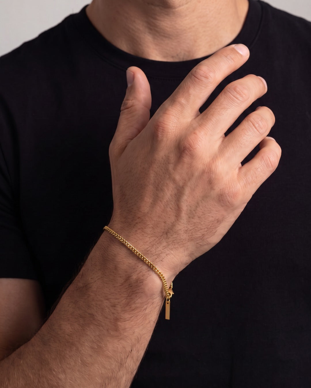 Fine 18K gold Cuban chain bracelet on a man's wrist against a black t-shirt