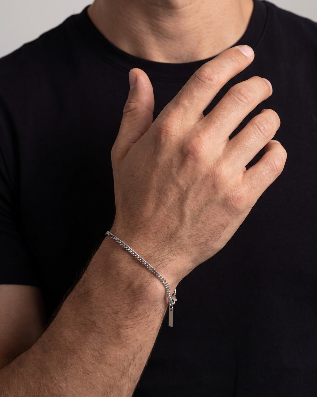 Fine silver Cuban chain bracelet on a man's wrist against a black t-shirt