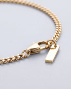 Macro close-up of fine gold Cuban links, lobster clasp and bar tag