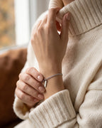 Women's fine silver Cuban bracelet worn with a cream knit sweater