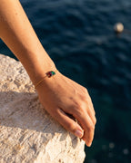 January birthstone bracelet in 14K gold, Siam red and emerald green stones, worn