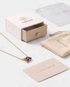 August birthstone necklace in 14K gold, peridot green and violet stones with Pureform gift packaging