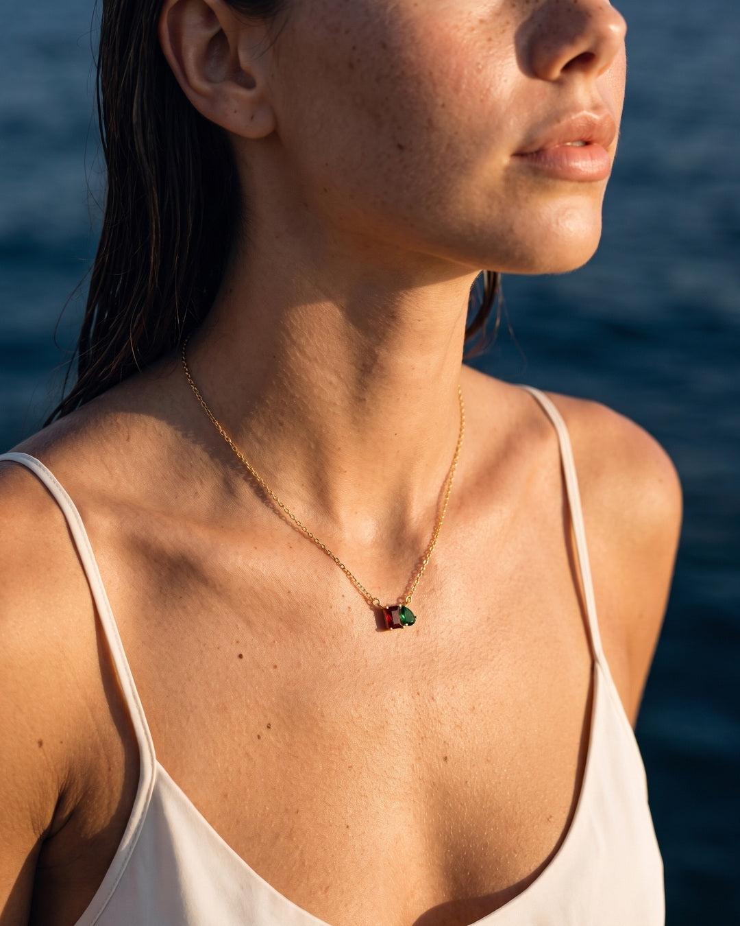 January birthstone necklace in 14K gold, Siam red and emerald green stones, worn