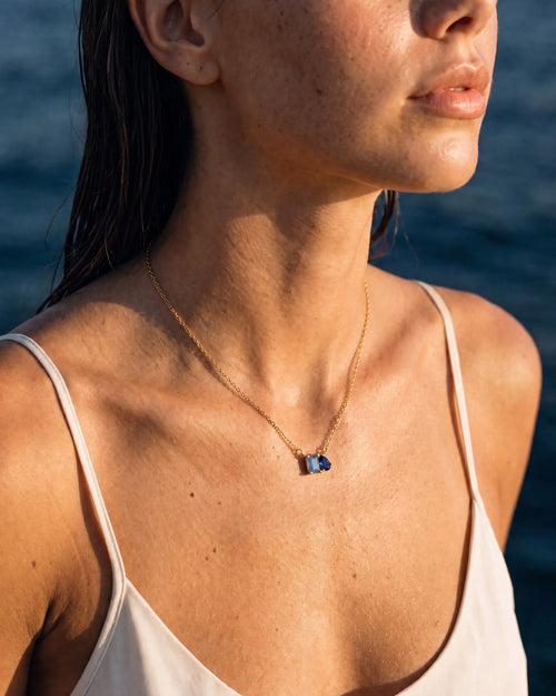 March birthstone necklace in 14K gold, light sapphire blue and sapphire blue stones, worn
