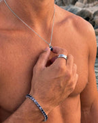 Grey Spinel pendant necklace, 1 carat, 925 silver — held between the fingers in beach light