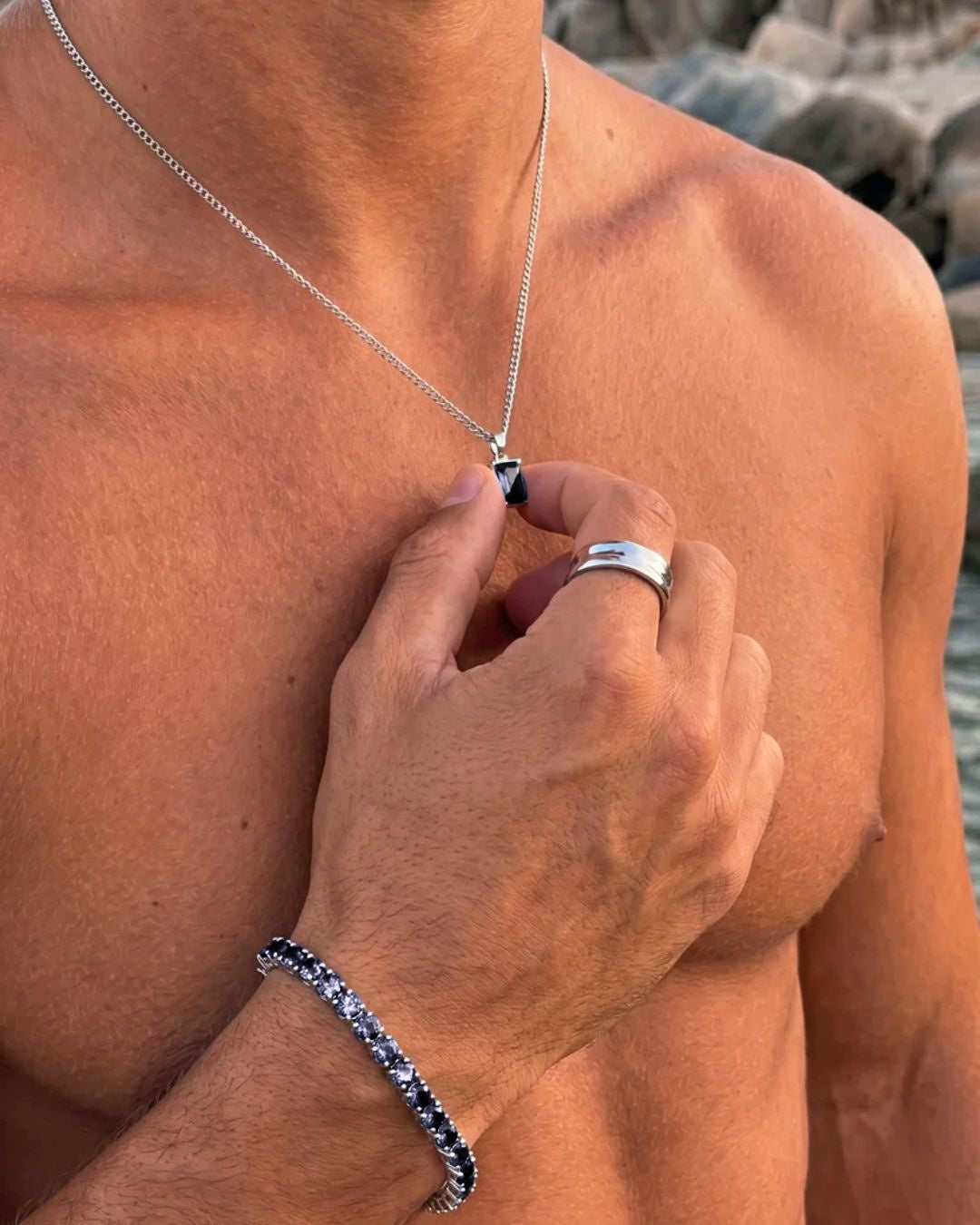 Grey Spinel pendant necklace, 1 carat, 925 silver — held between the fingers in beach light