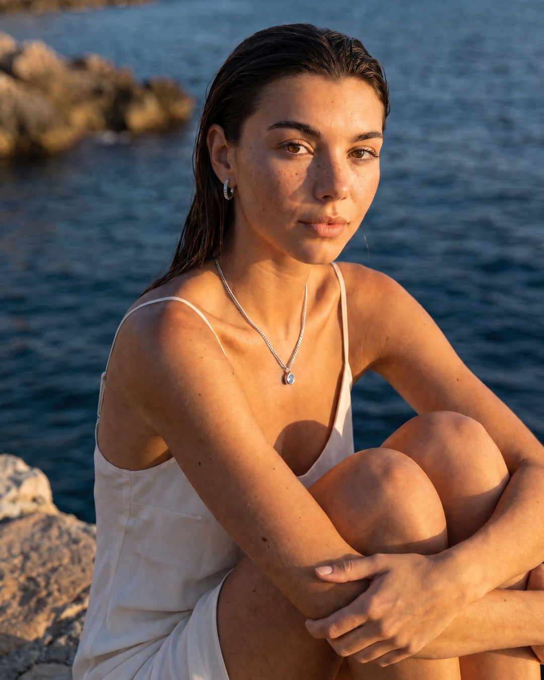 Aquamarine silver Lumière necklace styled with matching huggies by the sea