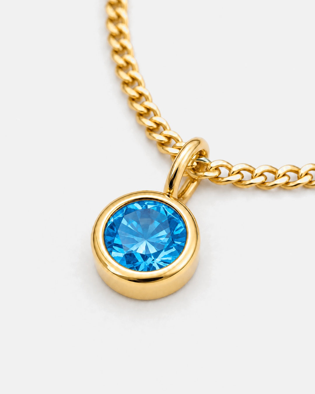 Close-up of the blue topaz bezel pendant on the gold Lumière necklace