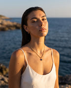 Sapphire gold Lumière necklace styled with matching huggies by the sea