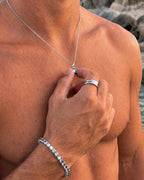 Moissanite pendant necklace, 1 carat, 925 silver — held between the fingers in beach light