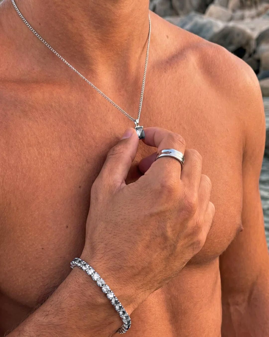 Moissanite pendant necklace, 1 carat, 925 silver — held between the fingers in beach light