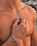 Royal Blue pendant necklace, 1 carat, 925 silver — held between the fingers in beach light