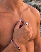 Ruby pendant necklace, 1 carat, 925 silver — held between the fingers in beach light